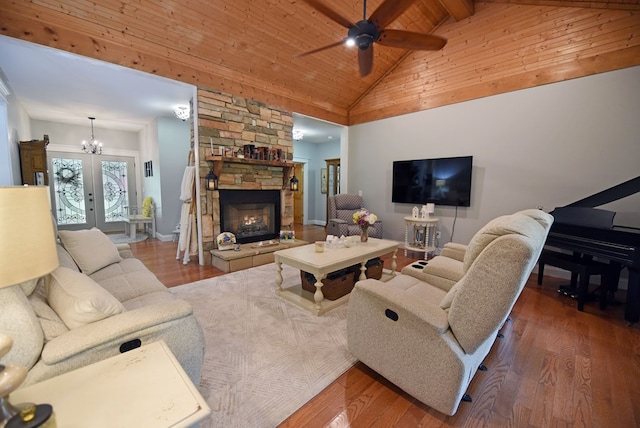 living room featuring dark wood-type flooring, french doors, ceiling fan with notable chandelier, a fireplace, and wooden ceiling