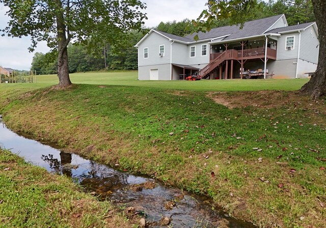 back of property with a wooden deck and a lawn