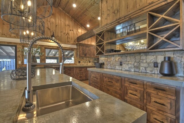 kitchen featuring a sink, high vaulted ceiling, wood ceiling, and wood walls