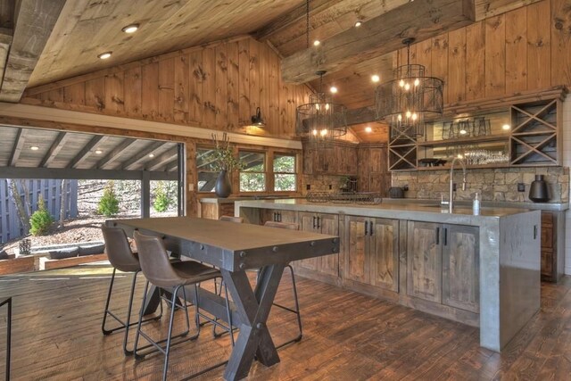 bar featuring dark wood-style flooring, a sink, wooden ceiling, high vaulted ceiling, and wooden walls