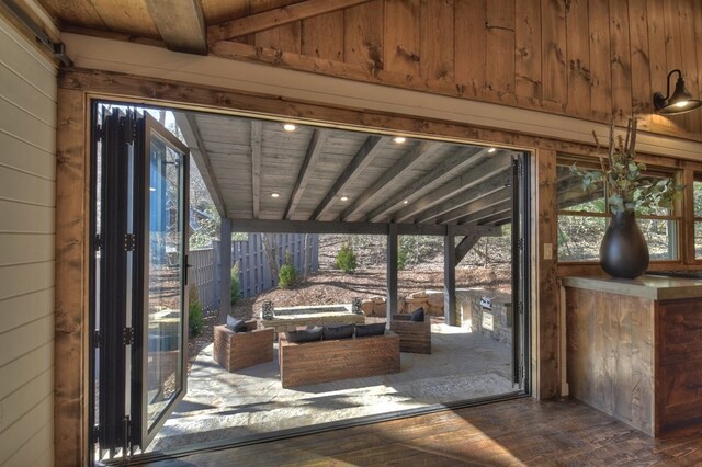 doorway to outside featuring wood walls, plenty of natural light, wood ceiling, and dark wood finished floors