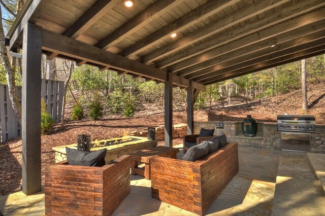 view of patio featuring fence, exterior kitchen, a grill, and an outdoor living space with a fire pit