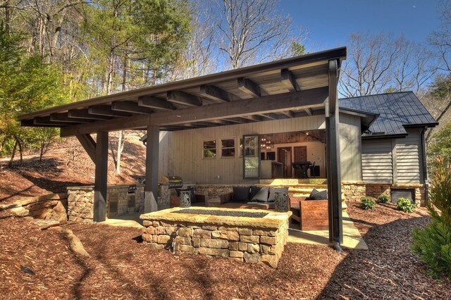 rear view of house featuring a fire pit and an outdoor kitchen