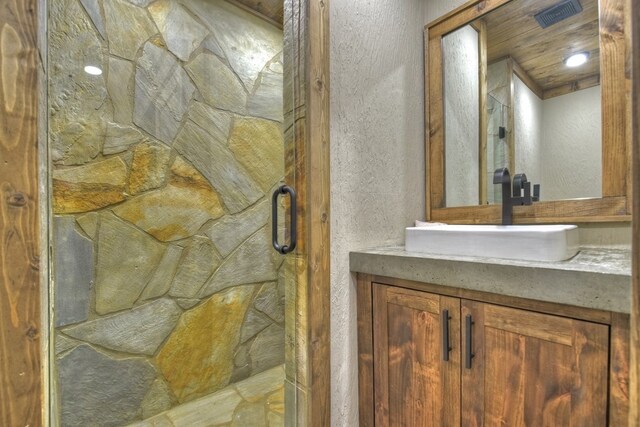 bathroom with vanity, a textured wall, and a stall shower
