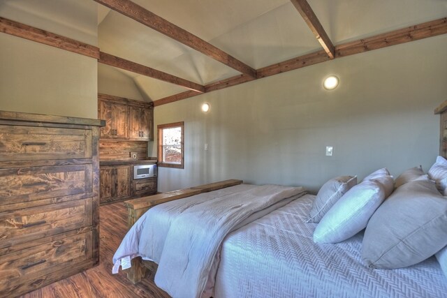 bedroom with lofted ceiling with beams and wood finished floors