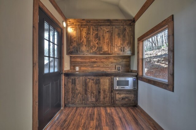 bar with dark wood-style flooring, stainless steel microwave, and lofted ceiling