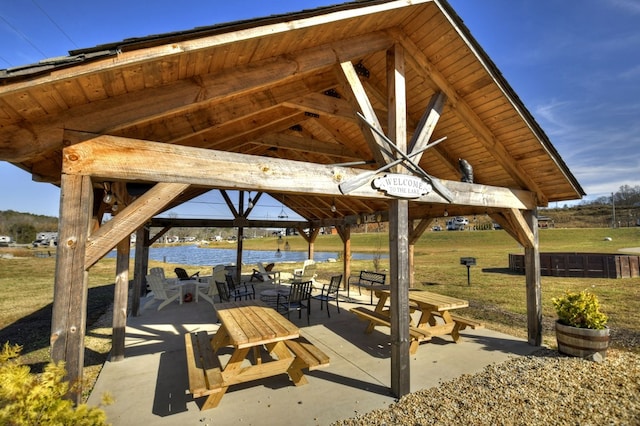 view of property's community featuring a gazebo, a water view, a patio, and a lawn