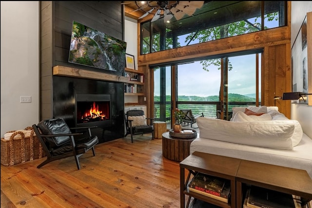 interior space featuring ceiling fan, hardwood / wood-style flooring, wood walls, a fireplace, and a towering ceiling