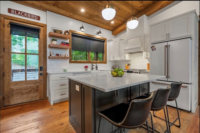 kitchen with wooden ceiling, light wood-style flooring, premium range hood, freestanding refrigerator, and a center island