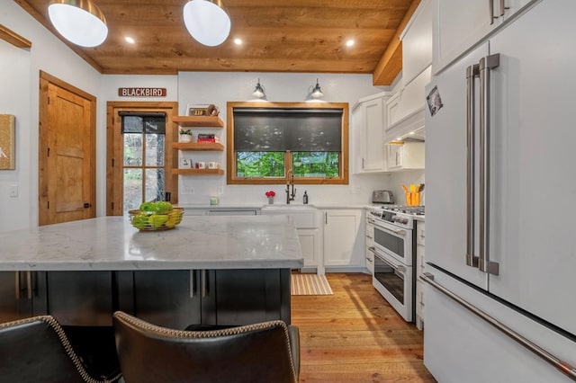 kitchen with premium appliances, wooden ceiling, light wood-type flooring, white cabinetry, and a sink