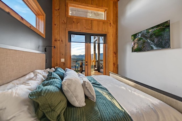 bedroom featuring access to outside, wooden walls, and french doors