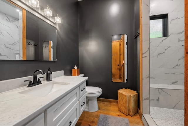 full bathroom with toilet, wood finished floors, vanity, baseboards, and a marble finish shower