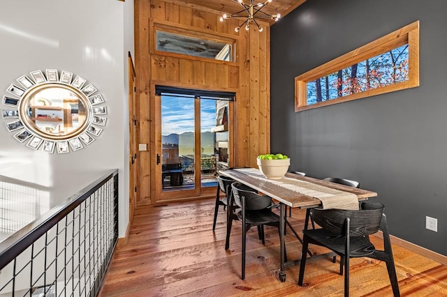 dining space with a towering ceiling, an inviting chandelier, and wood finished floors