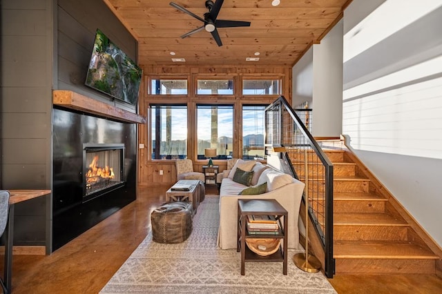 interior space with a large fireplace, wooden ceiling, stairs, and a ceiling fan