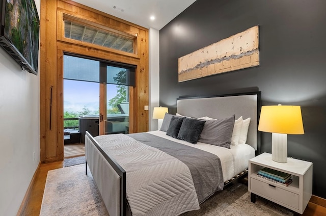 bedroom with access to outside, wood finished floors, and visible vents