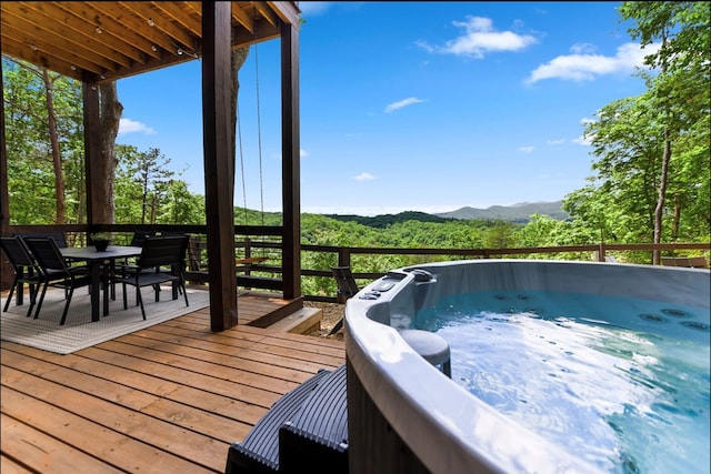 wooden terrace with outdoor dining area, a mountain view, and a hot tub