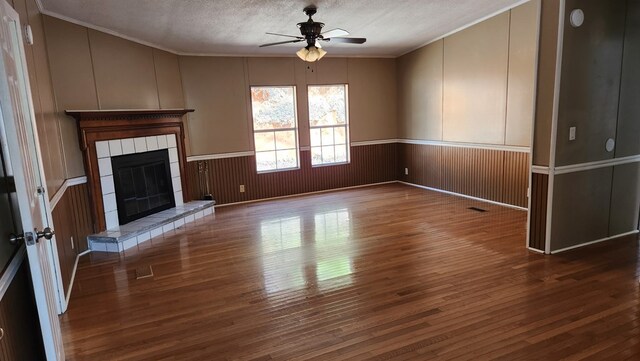 349 Kirby Ln, Murphy, NC 28906 - unfurnished living room with crown molding, a textured ceiling, a ceiling fan, a tiled fireplace, and hardwood / wood-style flooring