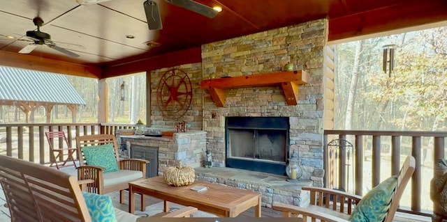 sunroom featuring ceiling fan and an outdoor stone fireplace