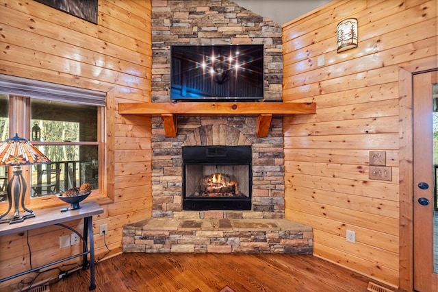 living room with hardwood / wood-style floors, wooden walls, and a fireplace