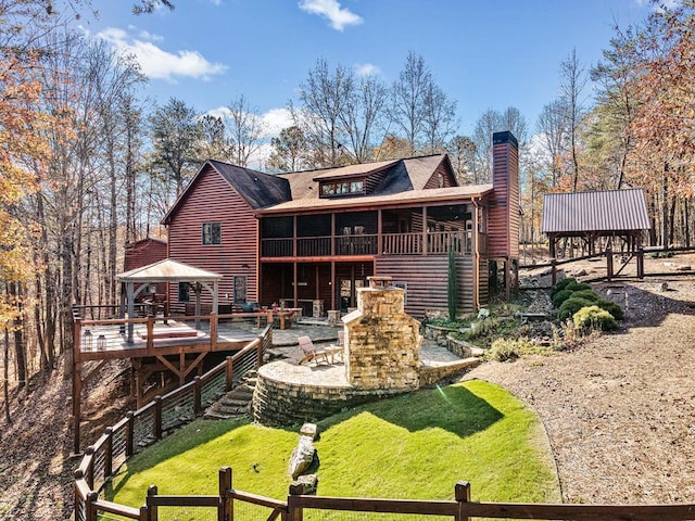 rear view of house featuring a lawn, a gazebo, a patio, a fireplace, and a sunroom