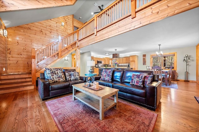 living room featuring high vaulted ceiling, a chandelier, and light hardwood / wood-style floors