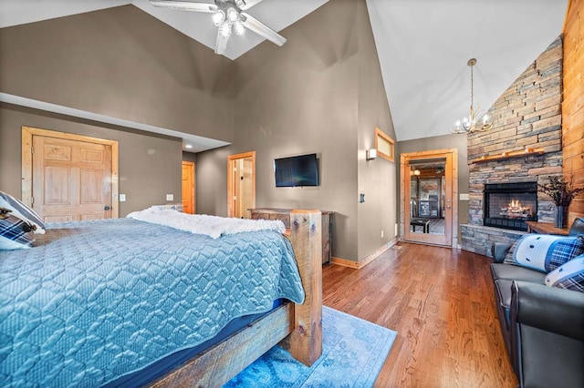 bedroom featuring hardwood / wood-style floors, high vaulted ceiling, ceiling fan with notable chandelier, and a fireplace