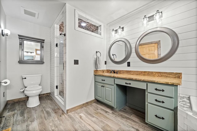 bathroom with toilet, a tile shower, vanity, and hardwood / wood-style floors