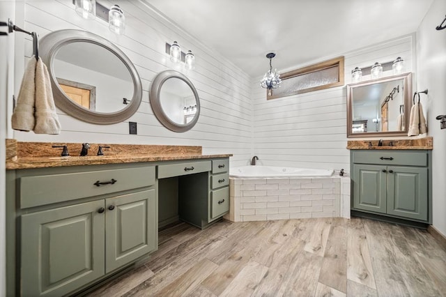 bathroom with hardwood / wood-style flooring, tiled bath, and vanity