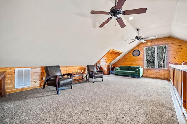 living area with lofted ceiling, wooden walls, ceiling fan, and carpet flooring