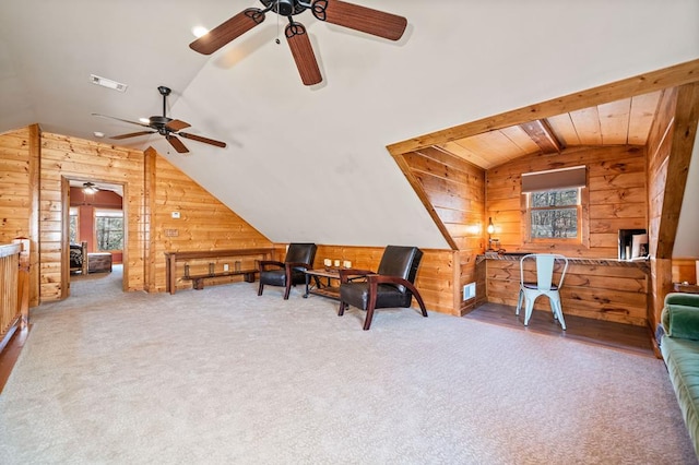 sitting room with wood walls, ceiling fan, vaulted ceiling, and carpet floors