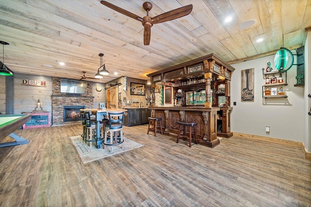 bar featuring wood ceiling, hardwood / wood-style floors, a stone fireplace, and hanging light fixtures