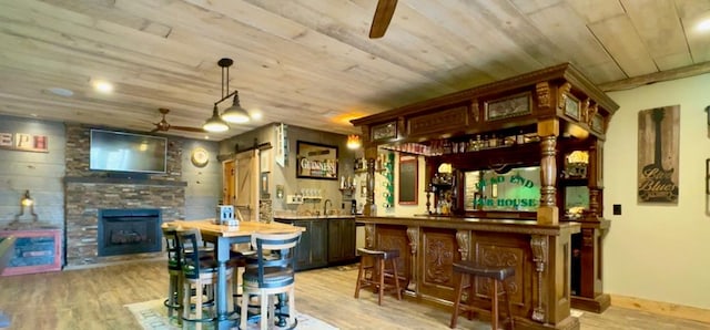 bar featuring wooden ceiling, ceiling fan, light hardwood / wood-style floors, and a barn door