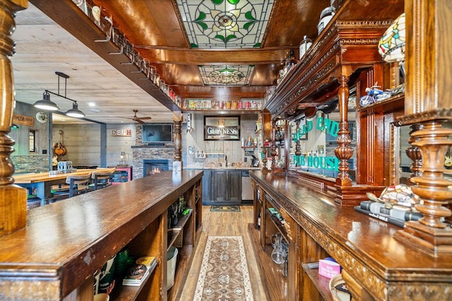 bar featuring stainless steel dishwasher, butcher block counters, light wood-type flooring, a fireplace, and ceiling fan