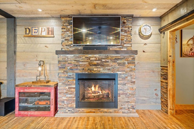 room details featuring wood walls, wood-type flooring, and a stone fireplace