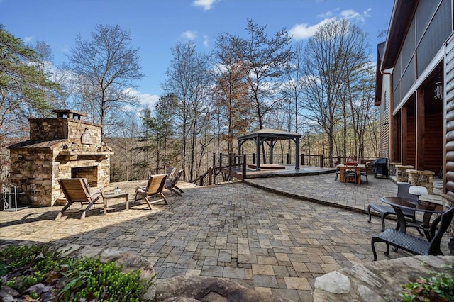 view of patio / terrace with an outdoor stone fireplace and a gazebo