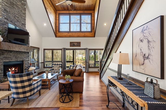 living room with high vaulted ceiling, a ceiling fan, a stone fireplace, wood finished floors, and recessed lighting
