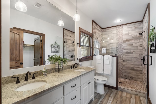 full bath featuring a shower stall, wood finished floors, toilet, and double vanity