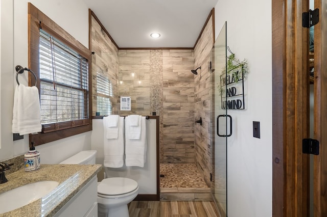 bathroom featuring a stall shower, toilet, vanity, and wood finished floors
