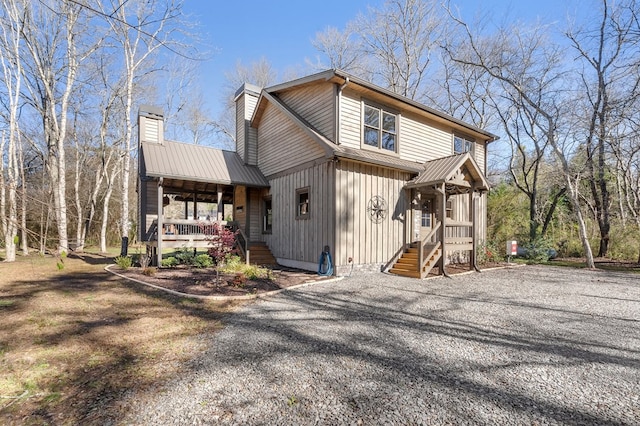 rustic home with covered porch, metal roof, a chimney, and board and batten siding