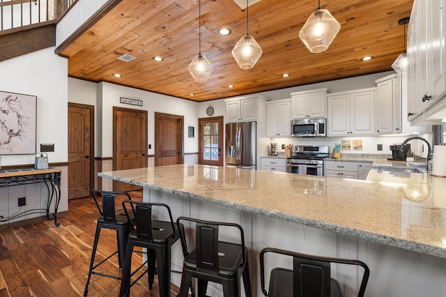kitchen featuring stainless steel appliances, a peninsula, a sink, dark wood finished floors, and white cabinetry