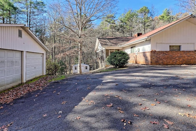 view of home's exterior with a garage and a storage unit