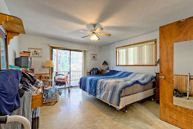 bedroom with access to outside, ceiling fan, and wood walls