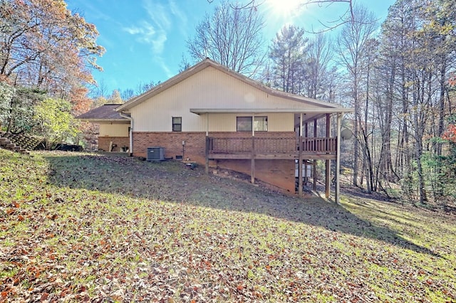 rear view of house featuring a lawn, cooling unit, and a deck