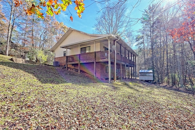 view of side of home featuring a yard, a deck, cooling unit, and a storage unit