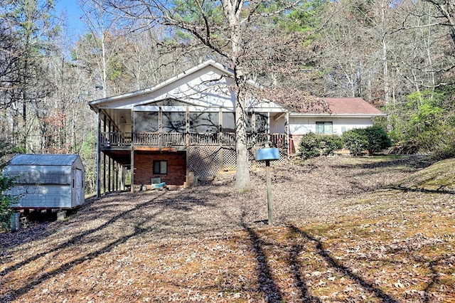 rear view of house with a wooden deck and a storage unit