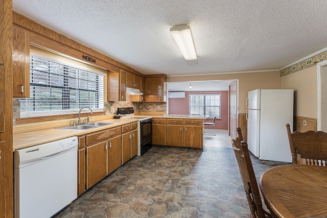 kitchen with a textured ceiling, kitchen peninsula, sink, and white appliances