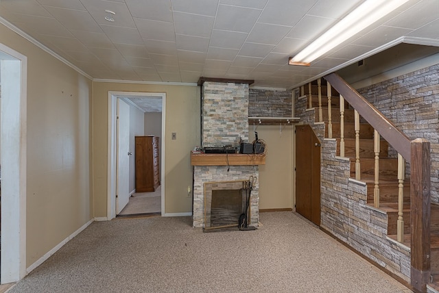 unfurnished living room featuring a stone fireplace, carpet floors, and ornamental molding