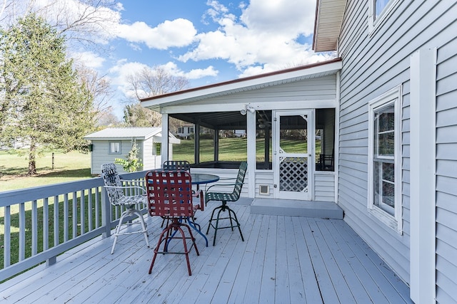 deck featuring an outbuilding, a yard, and a sunroom