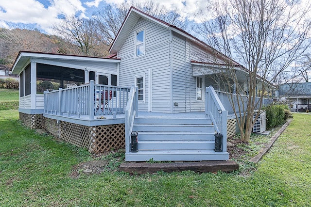 rear view of property featuring a sunroom, a yard, and a deck