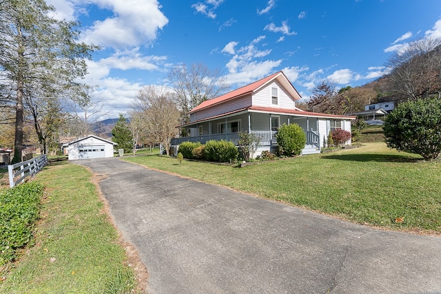 view of side of home with covered porch, an outbuilding, a garage, and a lawn